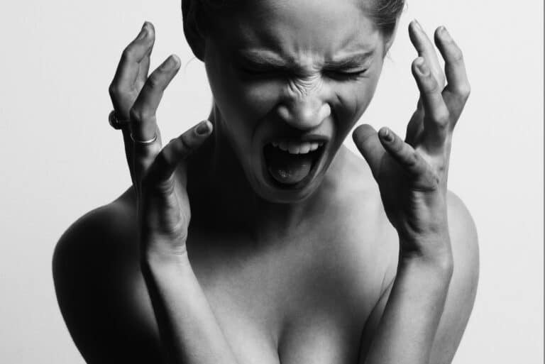 A woman holding her hands to her face and screaming in frustration.