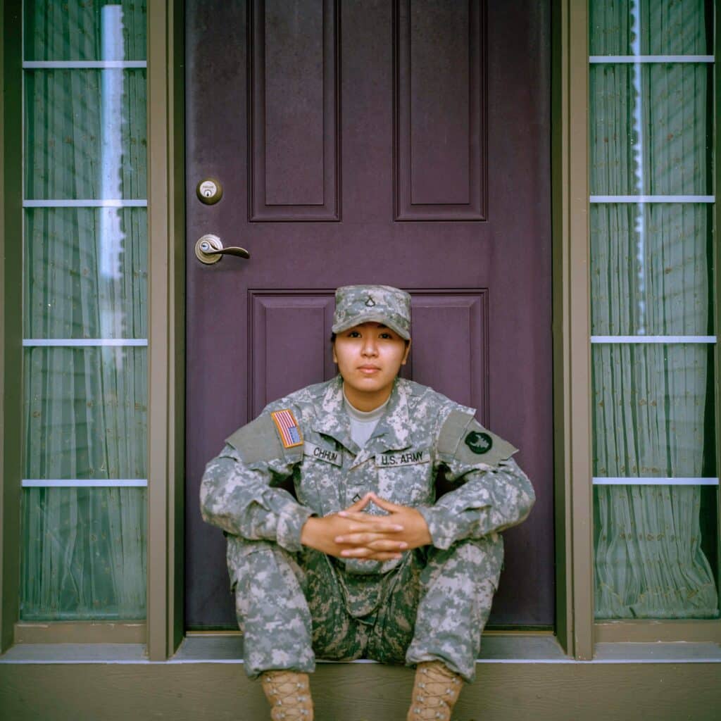 Latino women un U.S Army uniform sitting on a door step.
