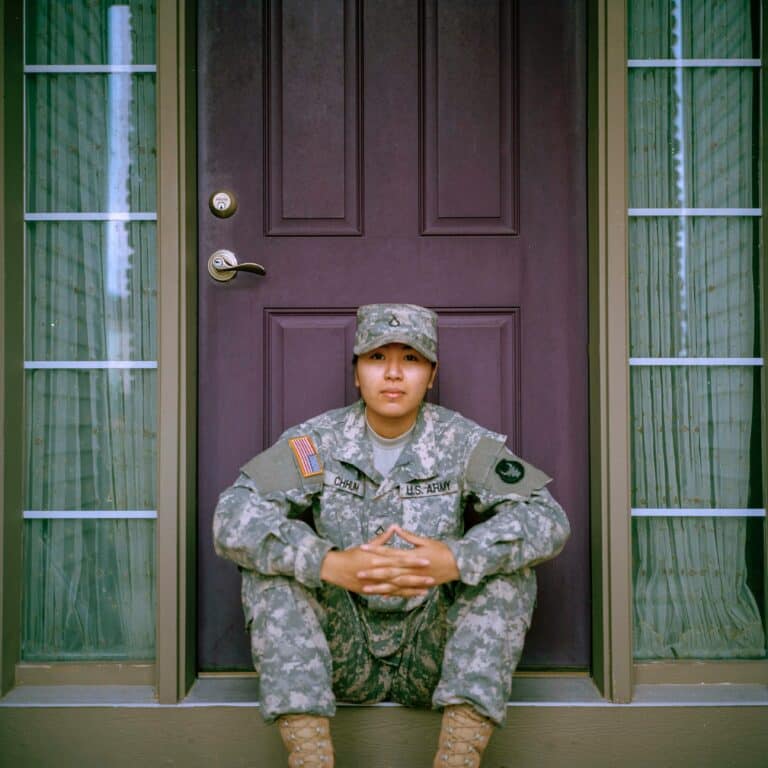 Latino women un U.S Army uniform sitting on a door step.